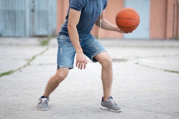 A man plays basketball in the street yard during the day