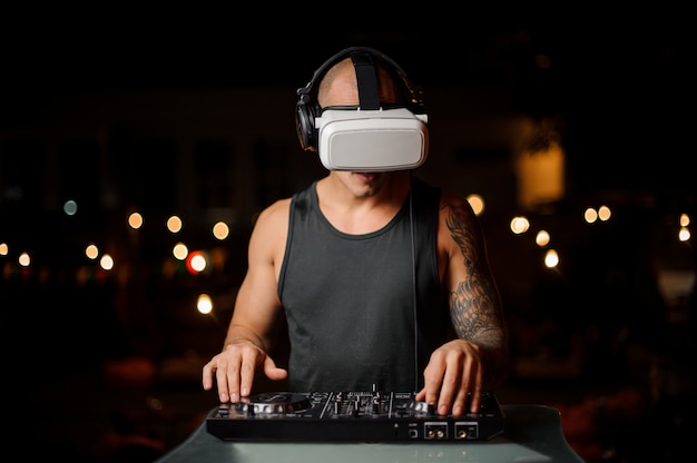 Man plays a DJ mixer with virtual reality glasses.