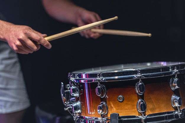 A man plays a snare drum with sticks, a drummer plays a percussion instrument, close up.