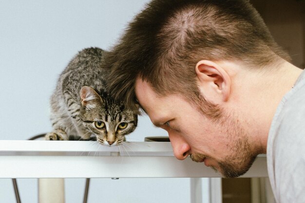 Foto l'uomo gioca con un gattino lo abbraccia