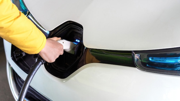 Man plugging in charger into an white electric car