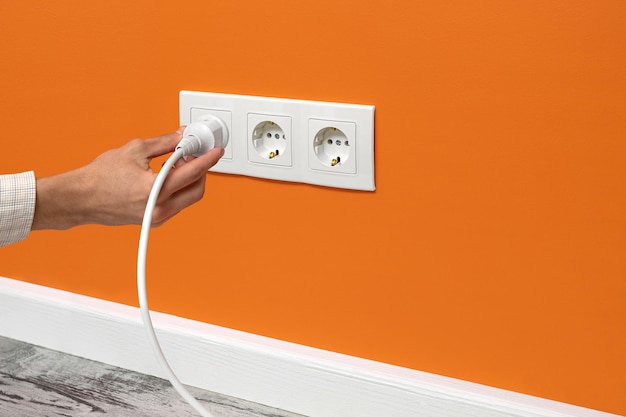 Man plugging cord into a electrical outlet