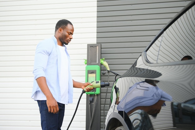 Man Plugging In Electric Car Outside Office In Car Park Charging