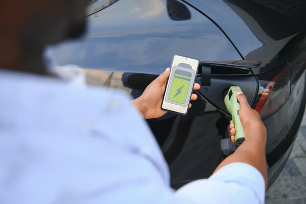 Photo man plugging in electric car outside office in car park charging