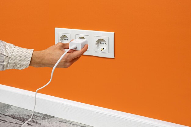 Man plugging phone adapter into a electrical outlet