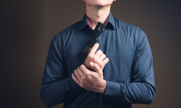 A man pointed a gun at himself on a brown surface