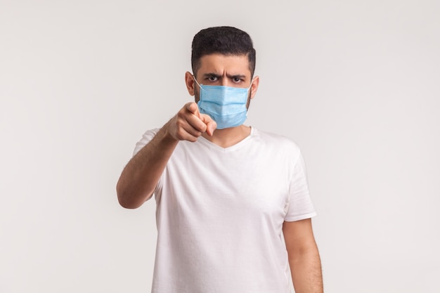 Man pointing at camera and wearing hygienic mask to prevent coronavirus