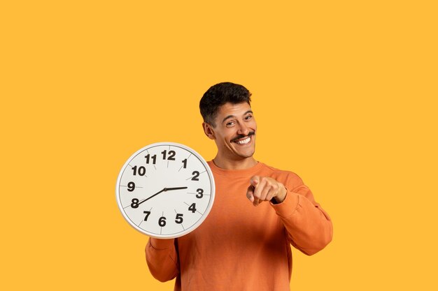 Photo man pointing at clock with happy expression