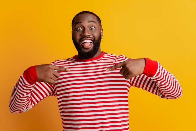 Man pointing finger himself excited open mouth posing on yellow background