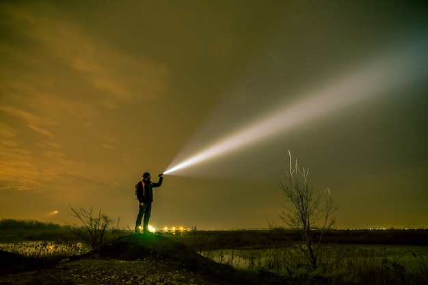 懐中電灯を夜空に向ける男。