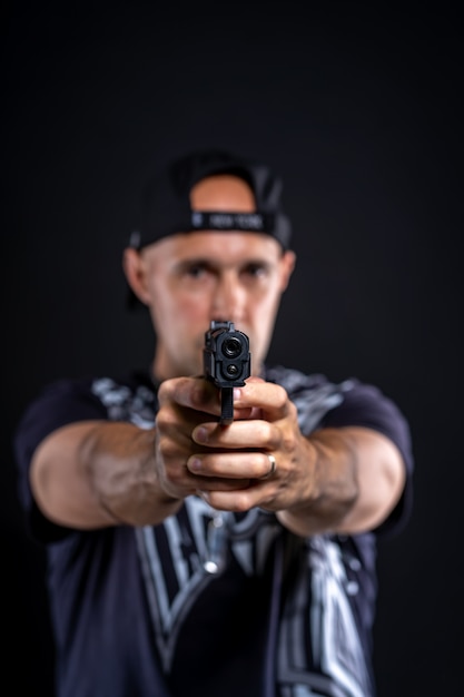 Photo man pointing gun at object, portrait on black background