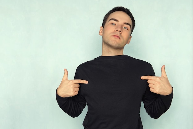 Man pointing at his tshirt can be used as a clothes design template on a blue background Tshirt with long sleeves black mocap for design