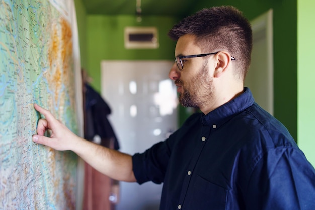 Photo man pointing at map on wall