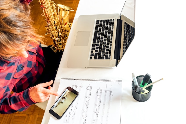 Man pointing the phone while doing the saxophone course online