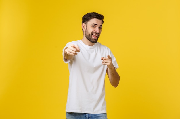 Man pointing showing copy space isolated on yellow wall. Casual handsome Caucasian young man.