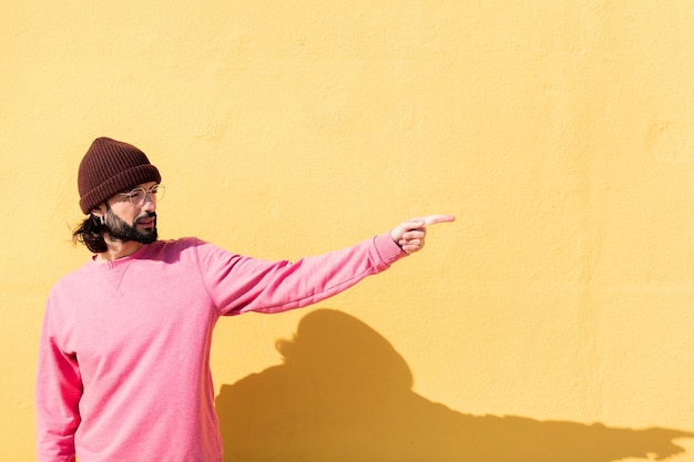 Man pointing to the side in a yellow background