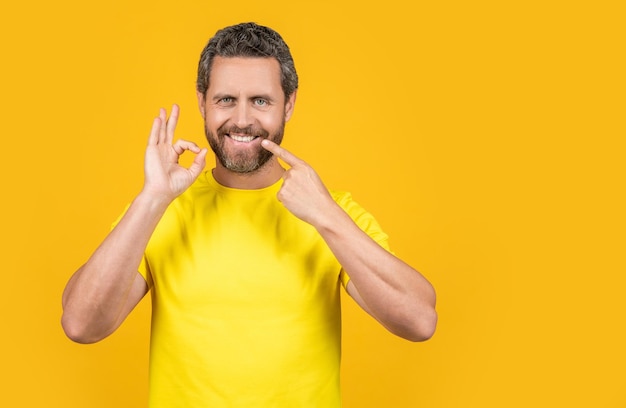 Man pointing at teeth smile on background copy space man pointing at teeth smile in studio