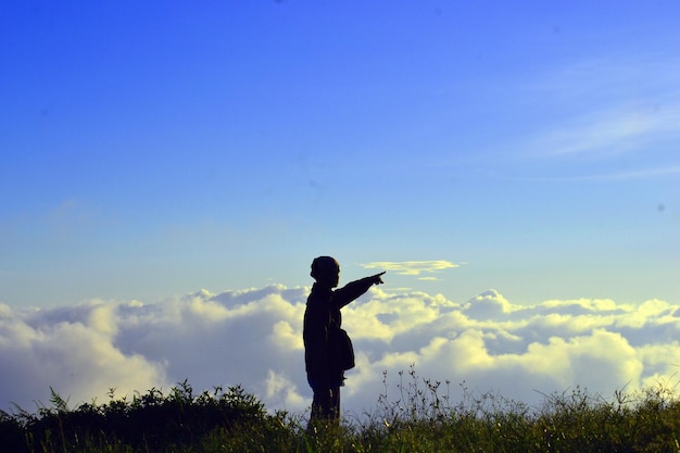 Photo man pointing while standing on grassy field against sky