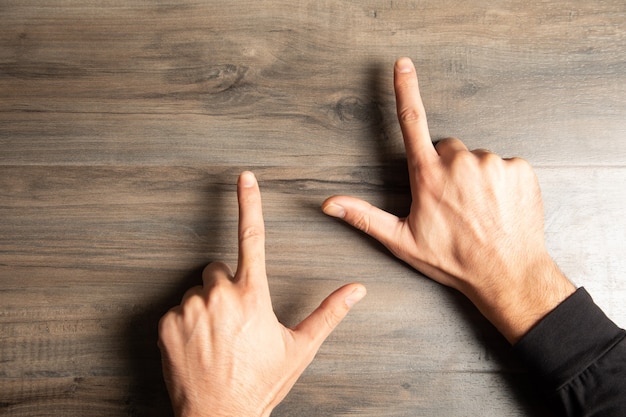 A man points his fingers on a wooden table