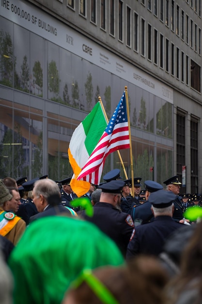 Photo a man in a police uniform is holding a flag and a green, white, and orange flag.