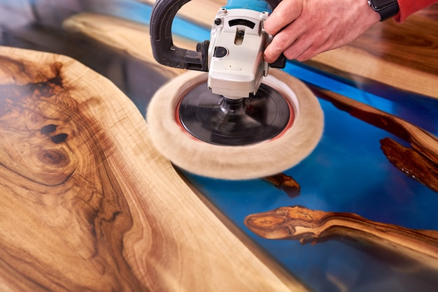 Man polishing epoxy table close up.