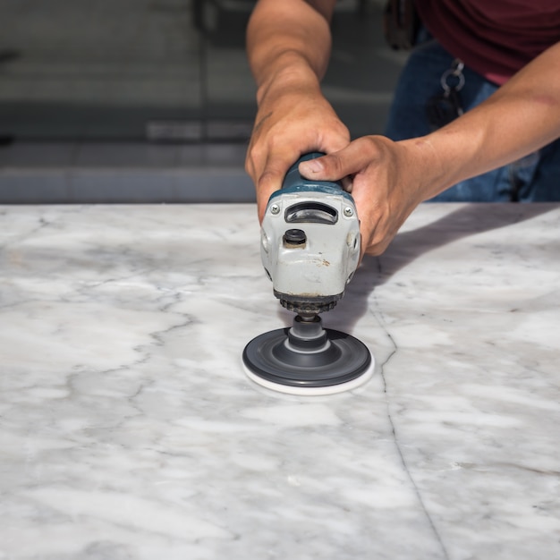 Man polishing marble stone table by small angle grinder