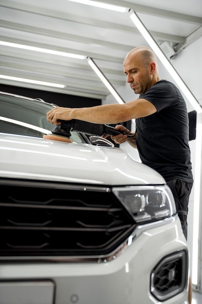 Man polishing a white car, wearing a black t-shirt