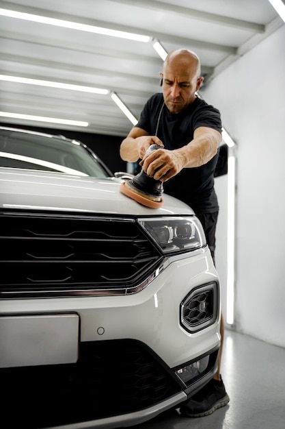 Man polishing a white car, wearing a black t-shirt