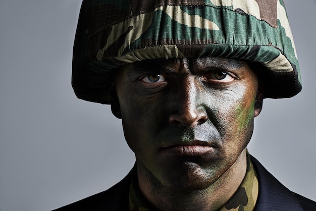 man portrait and soldier with camouflage for military war or battle on a gray studio background closeup of male person army or commander with face paint or helmet in undercover disguise on mockup