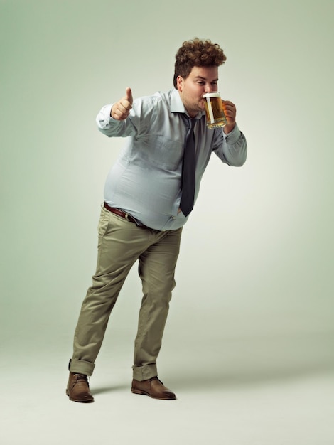 Photo man portrait and thumbs up with beer for celebration drink or party on a studio background male person or plus size model with like emoji yes sign or ok for alcohol satisfaction on mockup space