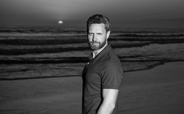 Man portrait with beard in sunset over sea unshaven guy on beach background