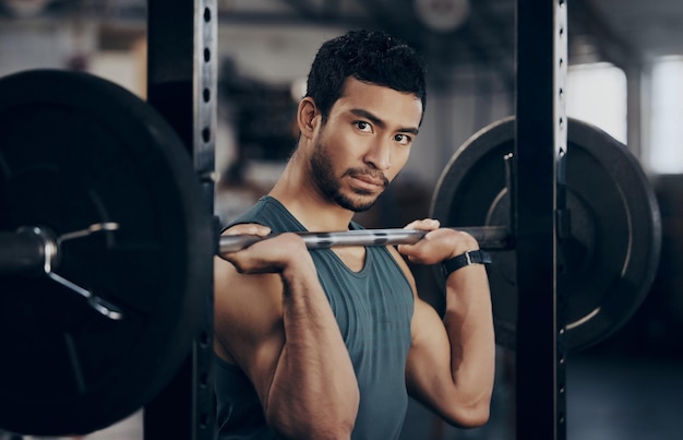 Foto man portret en druk op barbell voor training in de sportschool voor sterke spieren in een close-up mannelijke atleet oefening en gewichtheffen voor fitness in een club met apparatuur voor een gezond lichaam met cardio