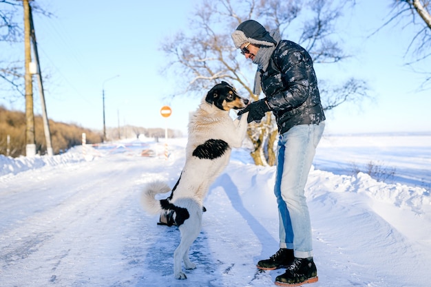 Man poseren met een vriendelijke hond in de sneeuw