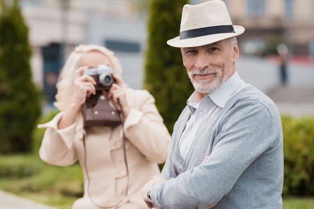 帽子でポーズをとる男。女性はカメラで写真を撮ります。