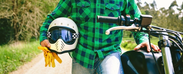 Man posing with motorcycle helmet and gloves