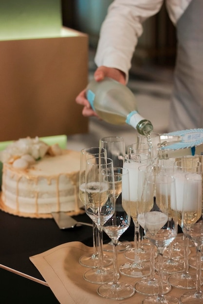 A man pouring champagne into glasses on a table.