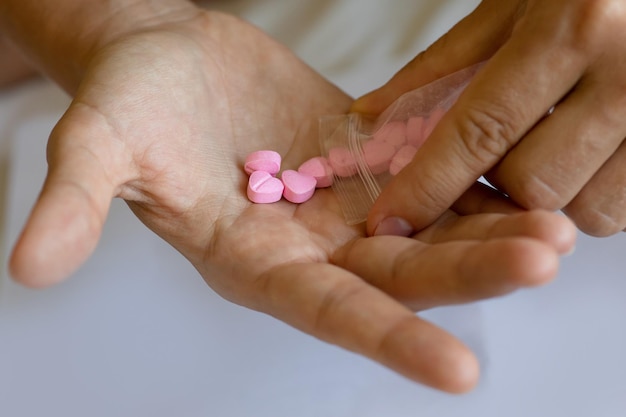 Man pouring heart shaped pills on palm from ziplock bag