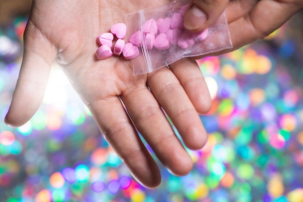 Man pouring heart shaped pills on palm from ziplock bag