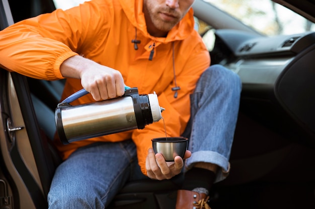 L'uomo versando una bevanda calda in tazza durante un viaggio su strada