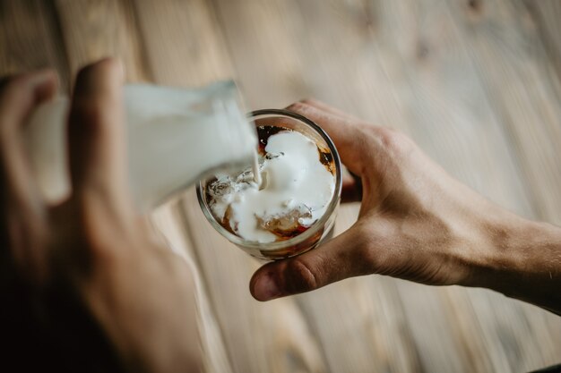 Man pouring milk in iced coffee