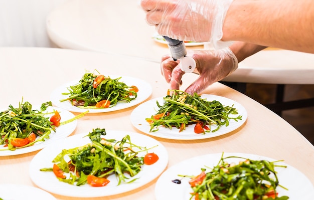 Man pouring sauce into plate with salad ingredients