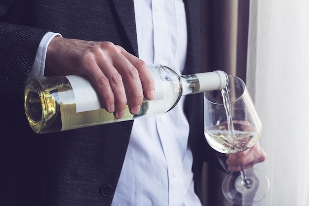 Man pouring white wine into a glass