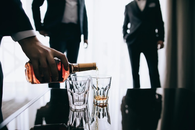 A man pours alcohol whiskey into glasses for his friends Relax in the bar