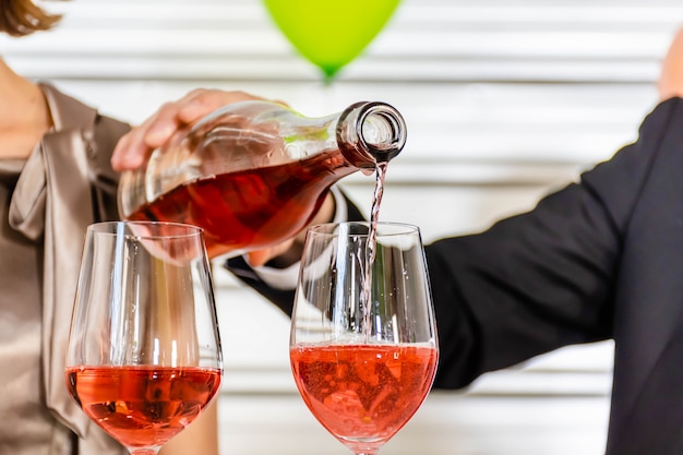 Photo a man pours champagne in glasses.