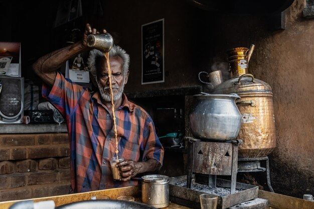 A man pours a drink in a kitchen.