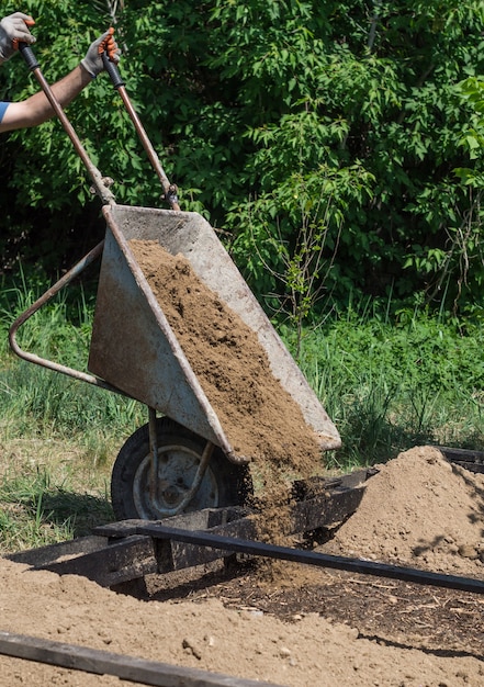 The man pours out the clay from the wheelbarrow