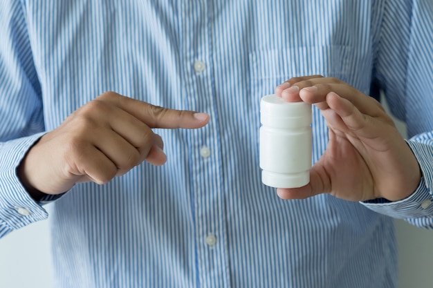  man pours the pills out of the bottle holding medicine