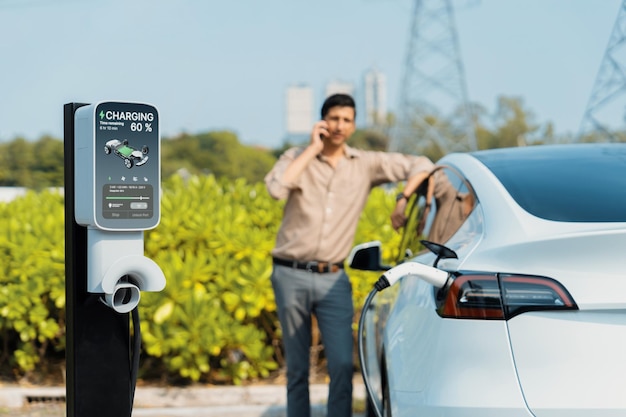 Man praat aan de telefoon terwijl hij een elektrische auto oplaadt bij een oplaadstation