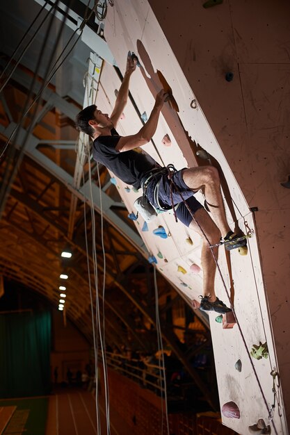 Man practicing rock-climbing on a rock wall indoors