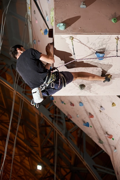 Man practicing rockclimbing on a rock wall indoors